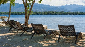 Une plage avec des chaises longues et une vue sur les montagnes.