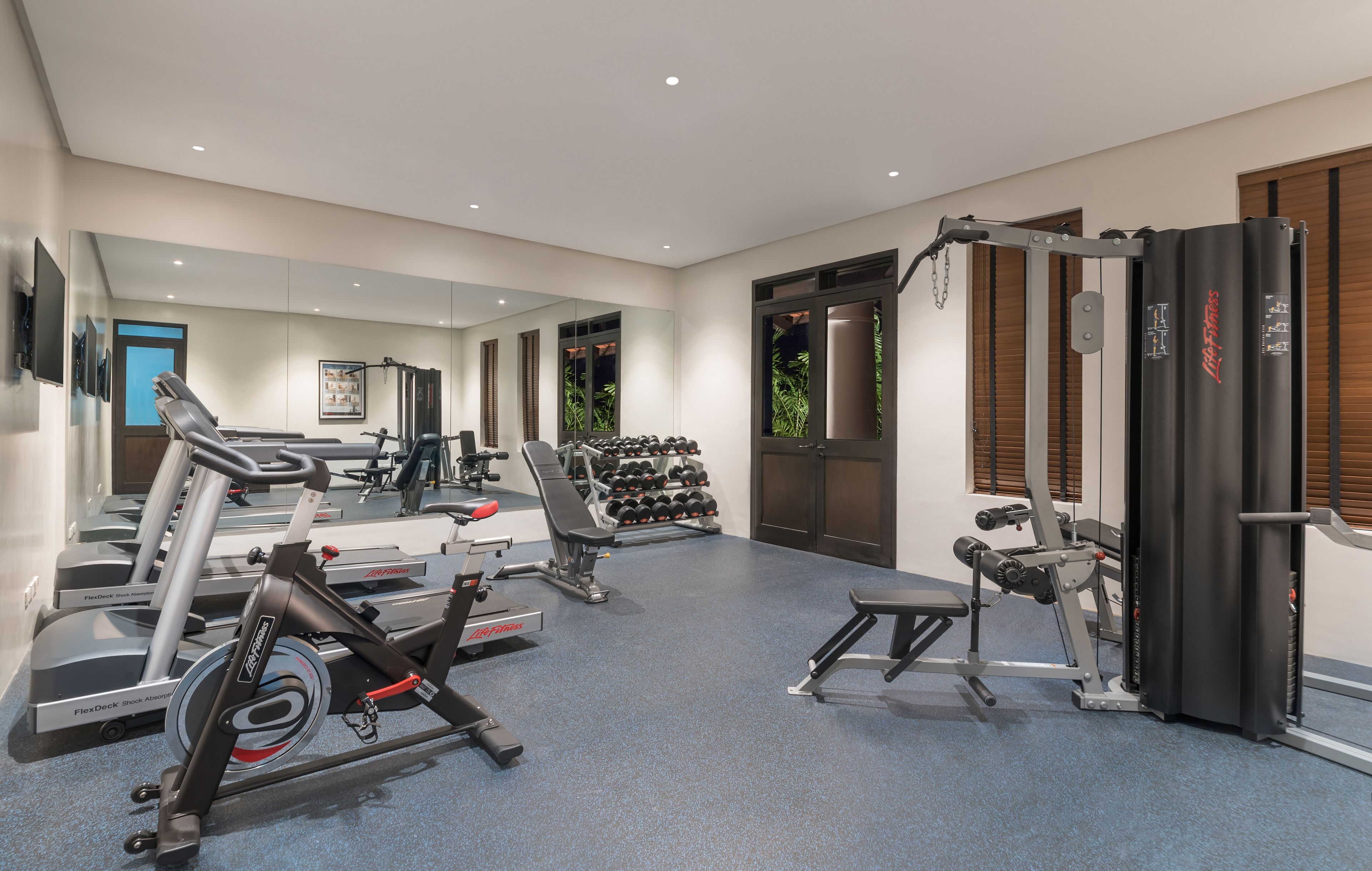 Une salle de sport moderne équipée de machines de cardio, de bancs de musculation et d’haltères.