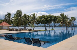 Una piscina al aire libre, sombrillas, sillones reclinables de piscina