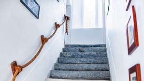 A staircase with a rope handrail, white walls, and framed pictures. - Great Ancient Renovated with fireplace and billiards (isigny sur mer)