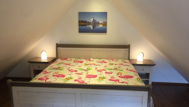 Een slaapkamer met een bed, twee nachtkastjes en een schilderij aan de muur.