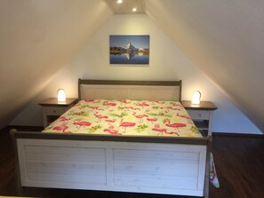 A bedroom with a bed, two bedside tables, and a painting on the wall.