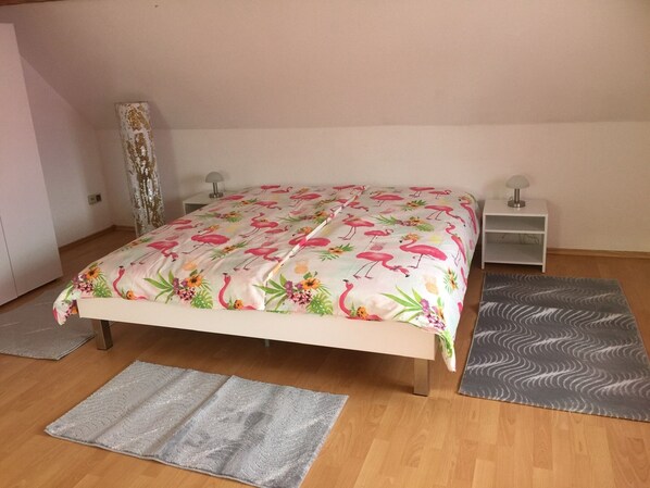 A bedroom with a bed, two bedside tables, a lamp on each table, and a grey rug on the floor.