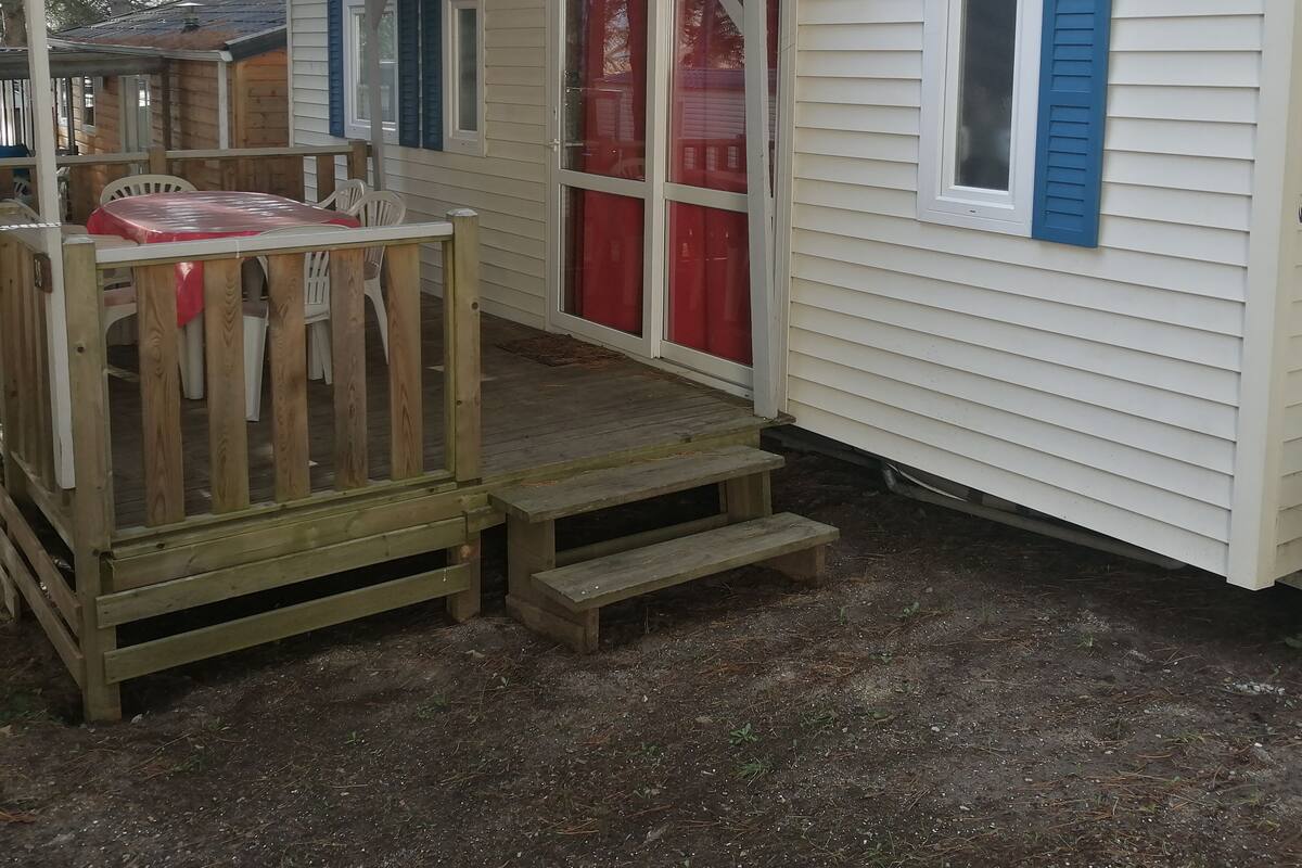 A small cabin with a porch, a red curtain, and a wooden deck.