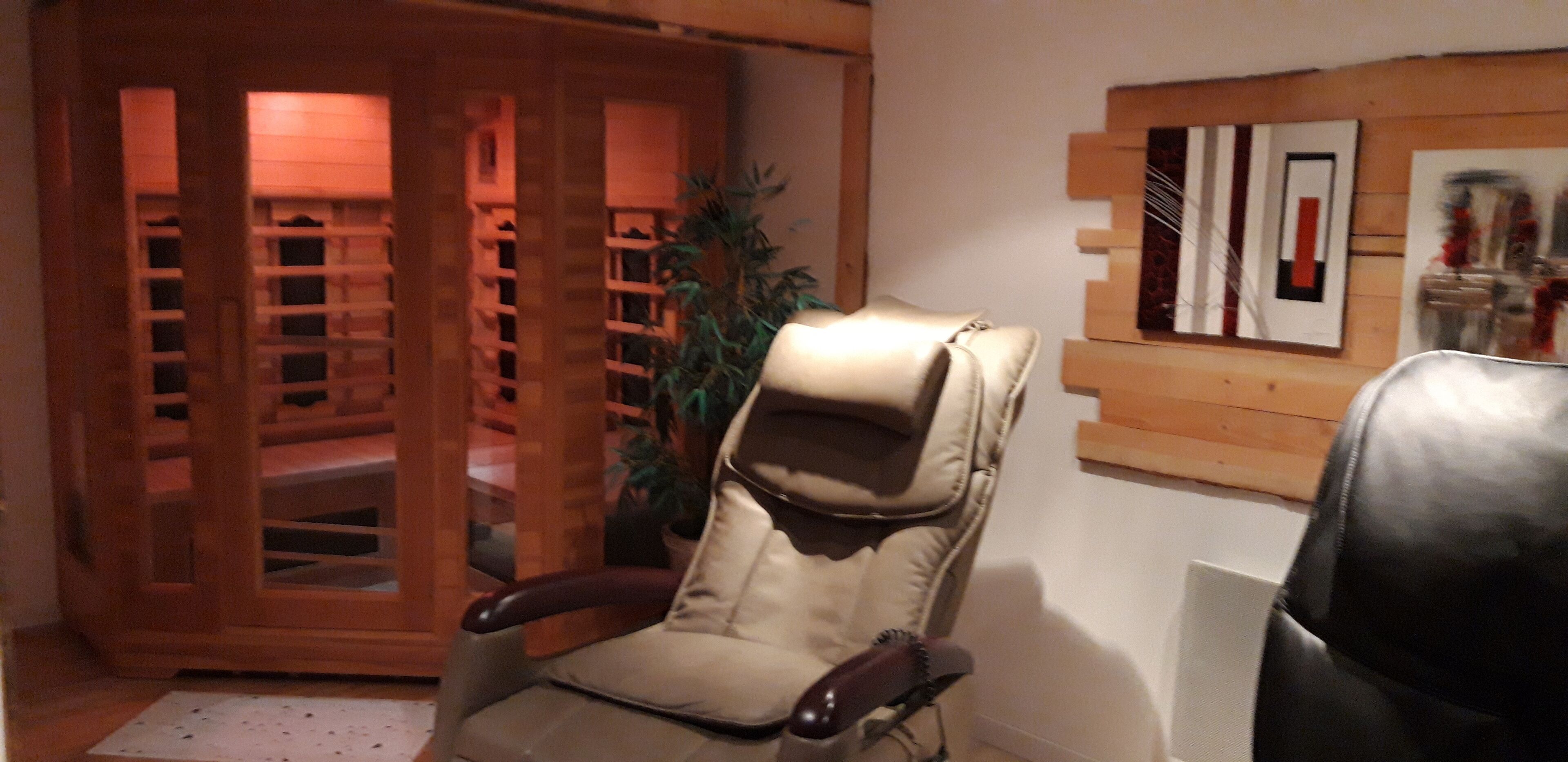 Une pièce comprenant un fauteuil en cuir beige, un meuble en bois doté de portes en verre et une œuvre d’art abstraite accrochée au mur.