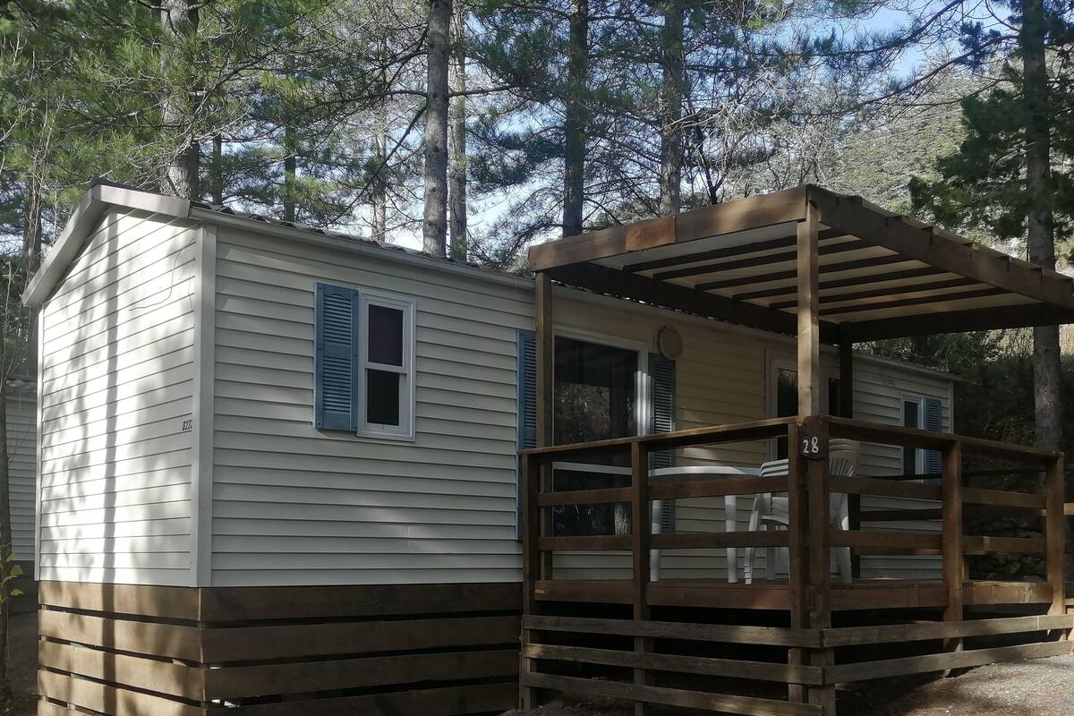 A mobile home with a wooden deck and a covered porch.