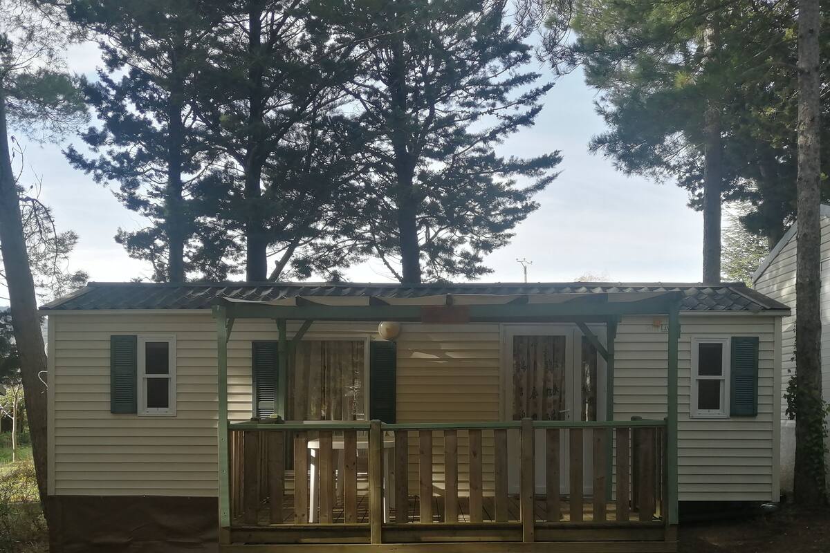 A mobile home with a wooden deck and a covered porch.