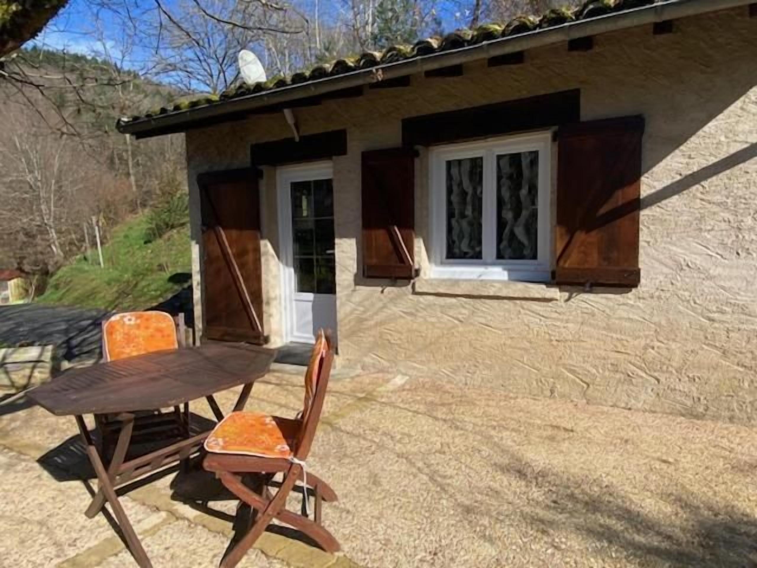Un edificio de piedra con una puerta y ventanas, una mesa y dos sillas afuera.