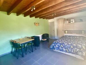 Una habitación con una cama, un escritorio con sillas, una mesita y una lámpara colgante.