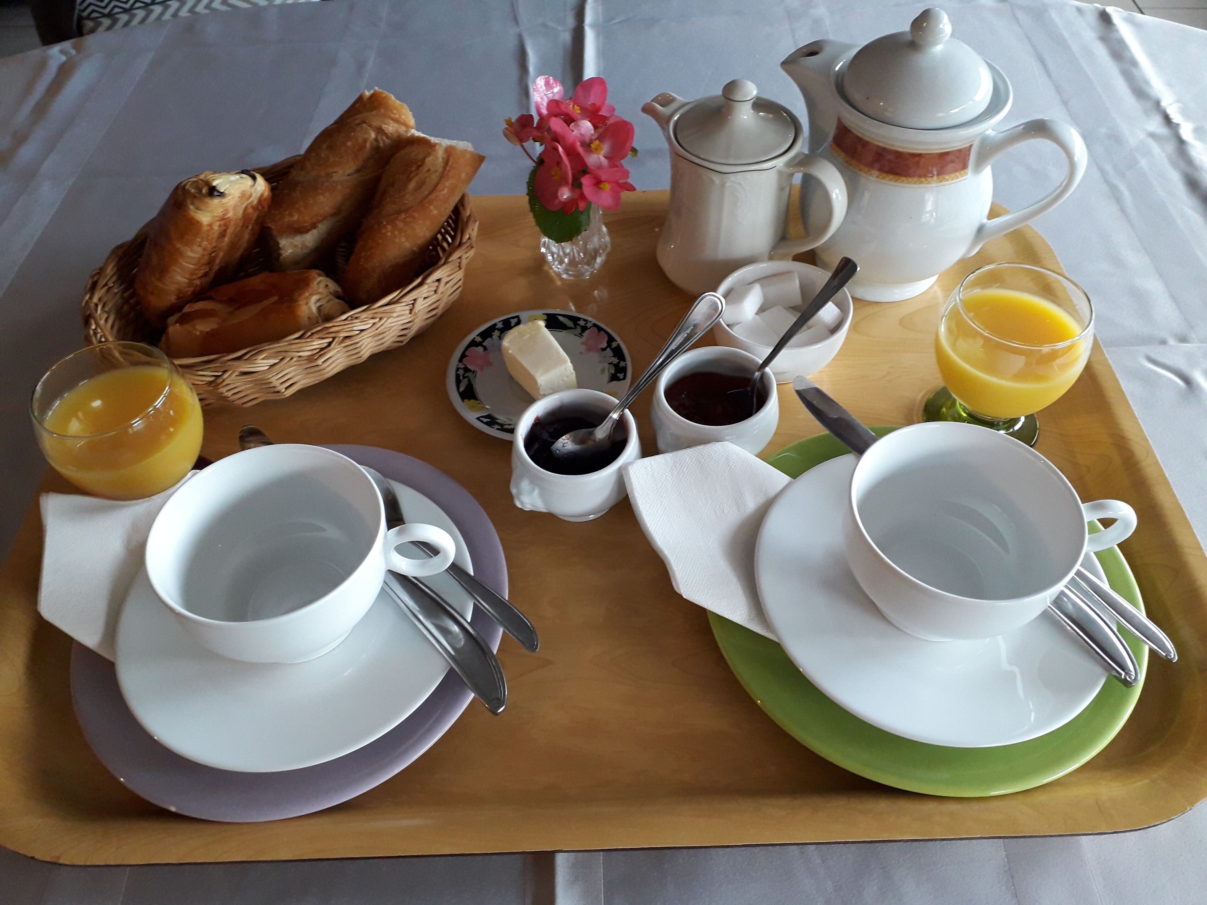 A breakfast tray with bread, butter, jam, coffee, and juice.