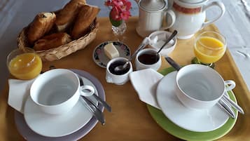 A breakfast tray with bread, butter, jam, coffee, and juice.