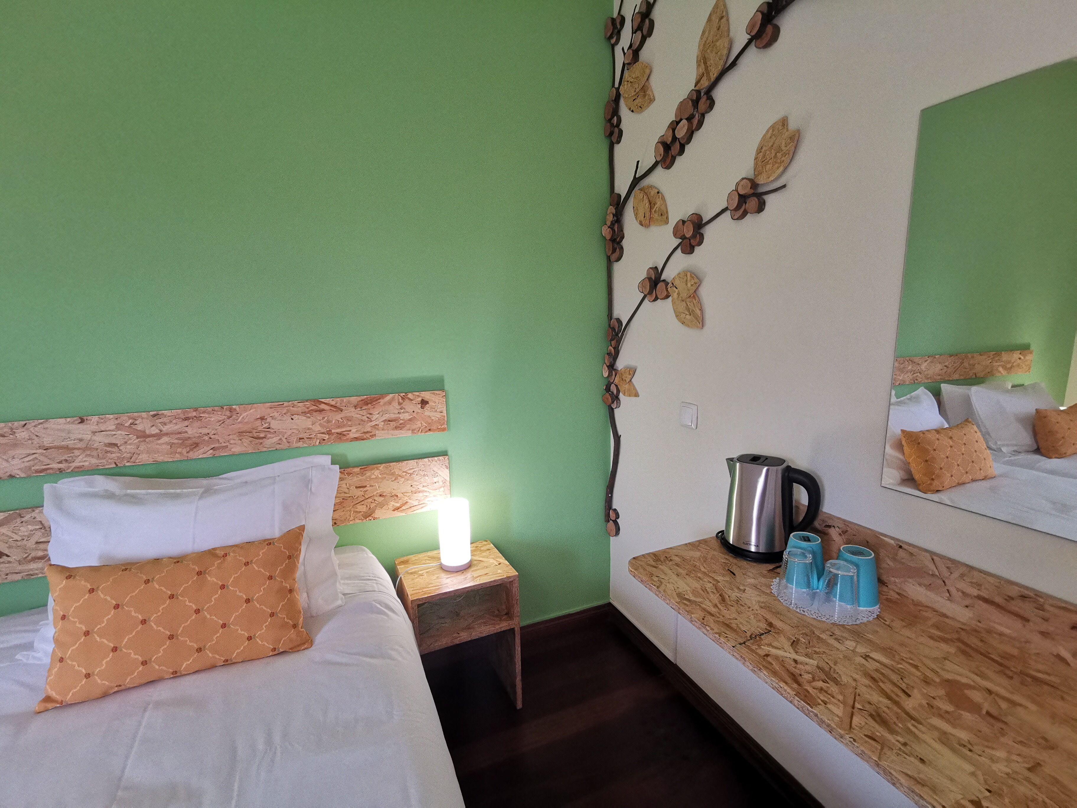 Un dormitorio con cama, mesita de noche y cómoda con espejo.