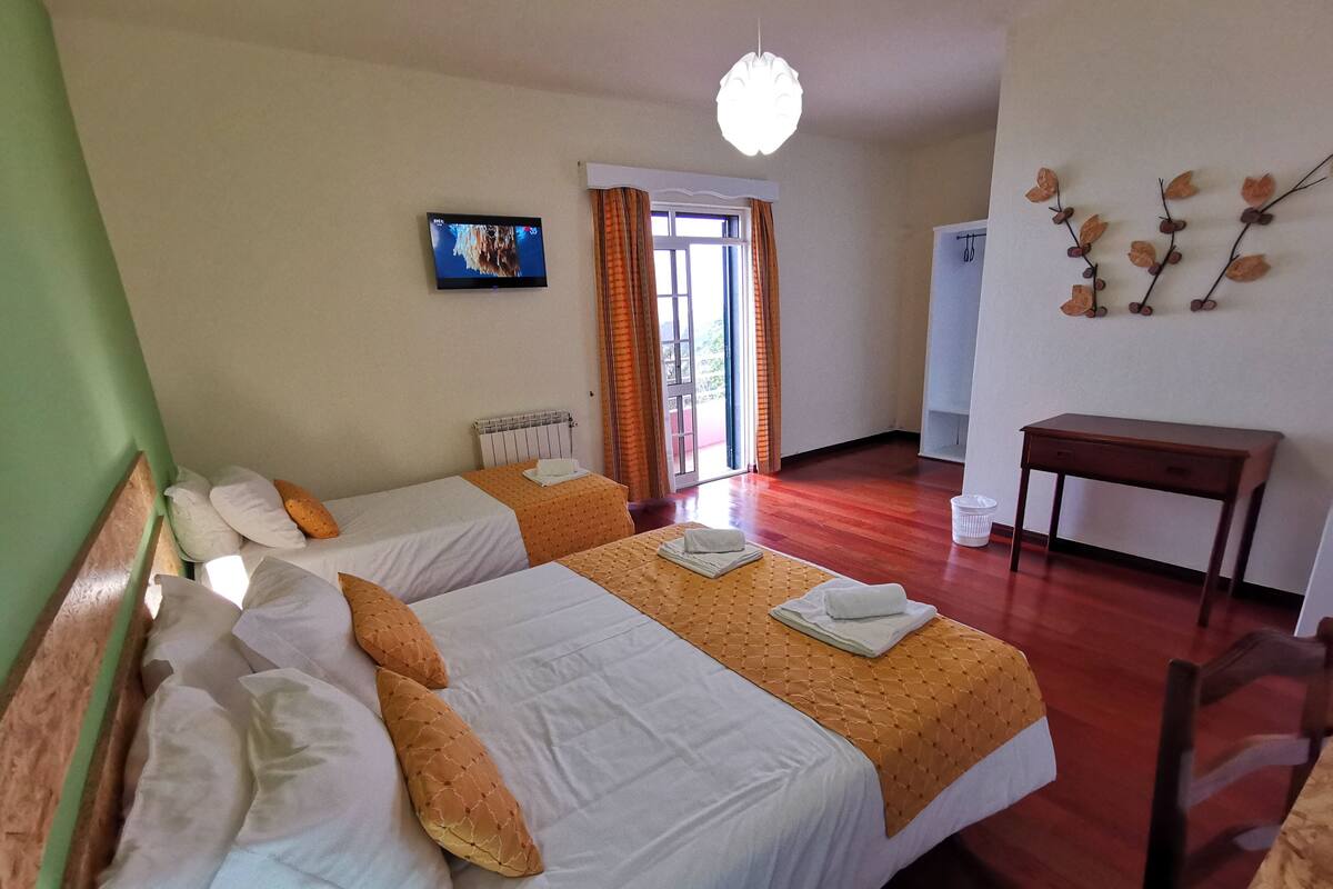 A hotel room with two beds, a TV, a desk, and a view of the outdoors.