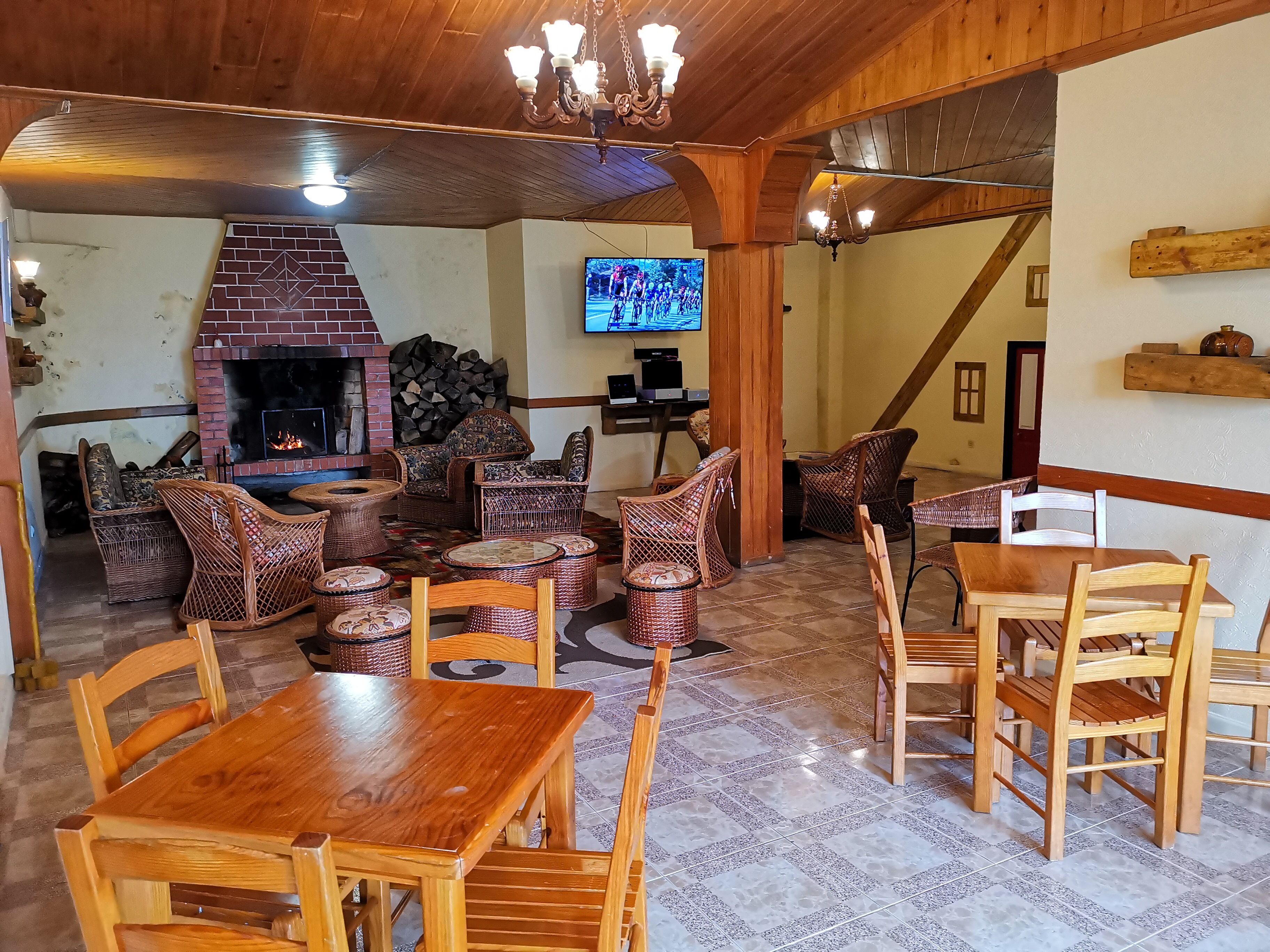 A cozy living room with a fireplace, wicker furniture, and a TV mounted on the wall.
