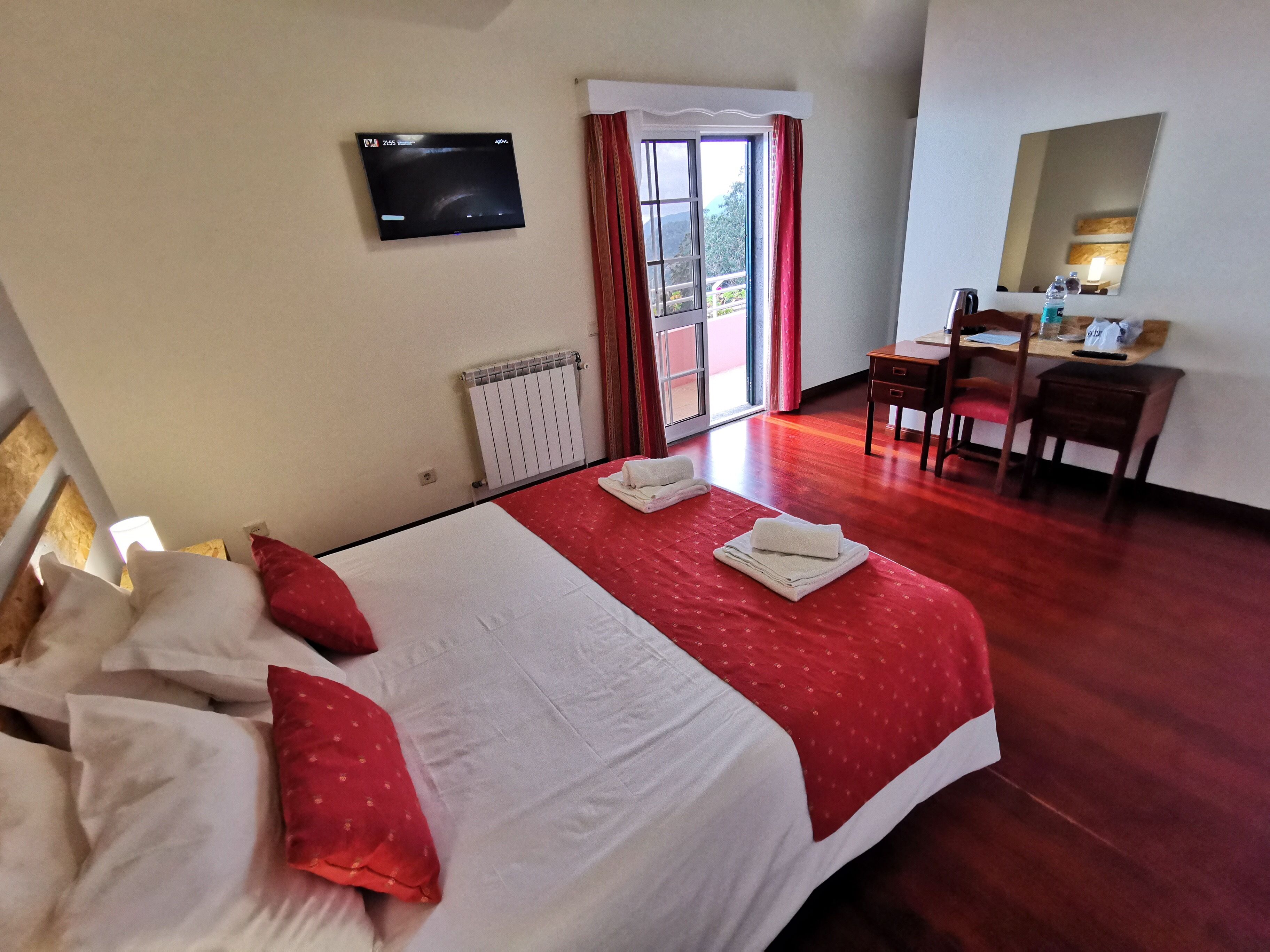 Een hotelkamer met een bed, een bureau, een stoel, een televisie en een raam met gordijnen.
