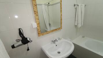 Ein Badezimmer mit einem weißen Waschbecken, einem Spiegel mit Holzrahmen, einem Handtuchhalter und einem Fön.