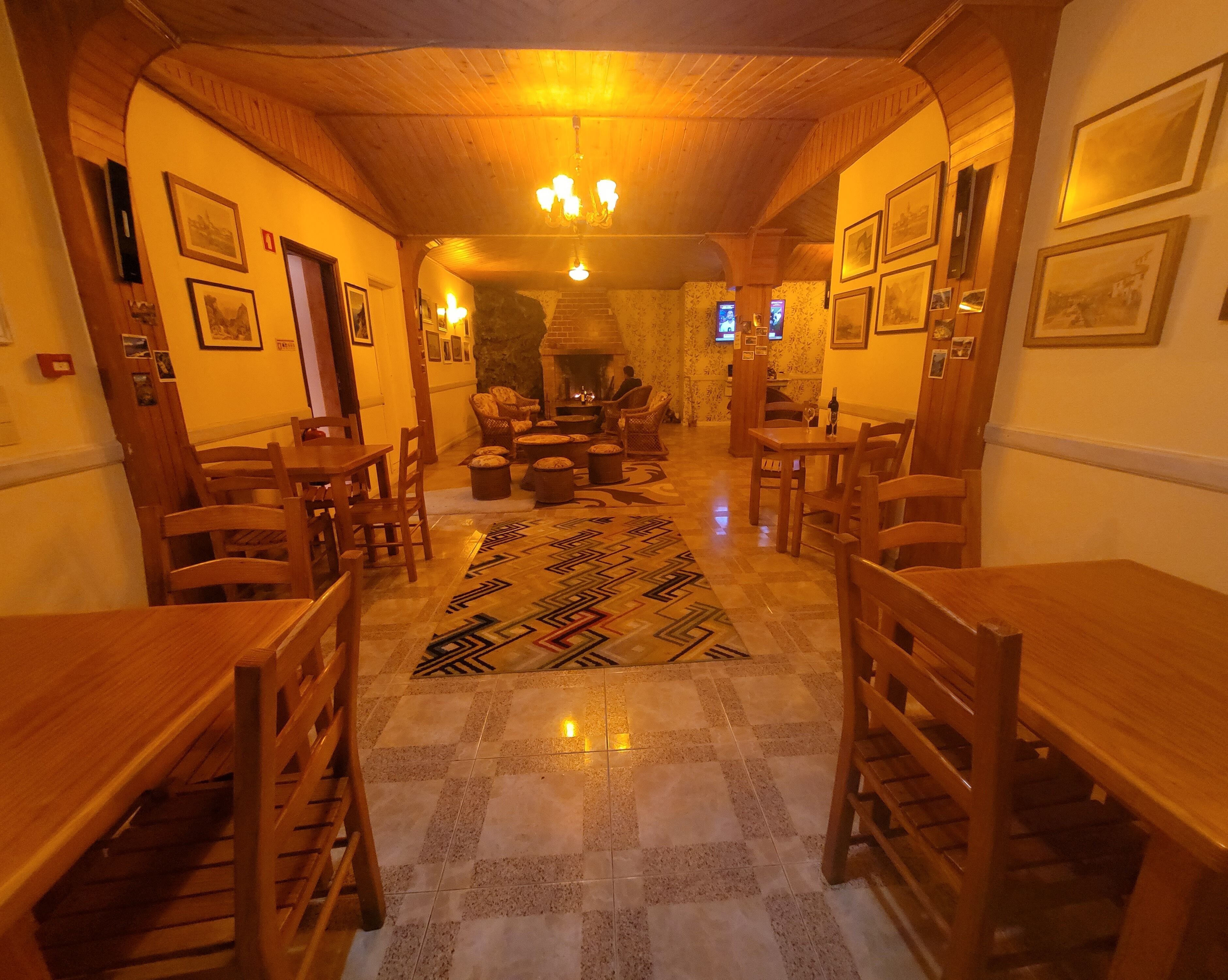 Una habitación acogedora con luz cálida, muebles de madera, un tapete estampado y cuadros en las paredes.