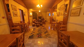 Una habitación acogedora con luz cálida, muebles de madera, un tapete estampado y cuadros en las paredes.