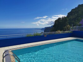 Una piscina al aire libre, sombrillas, sillones reclinables de piscina