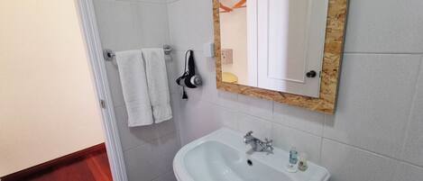 A bathroom with a white sink, a mirror, and two white towels hanging on a rack.