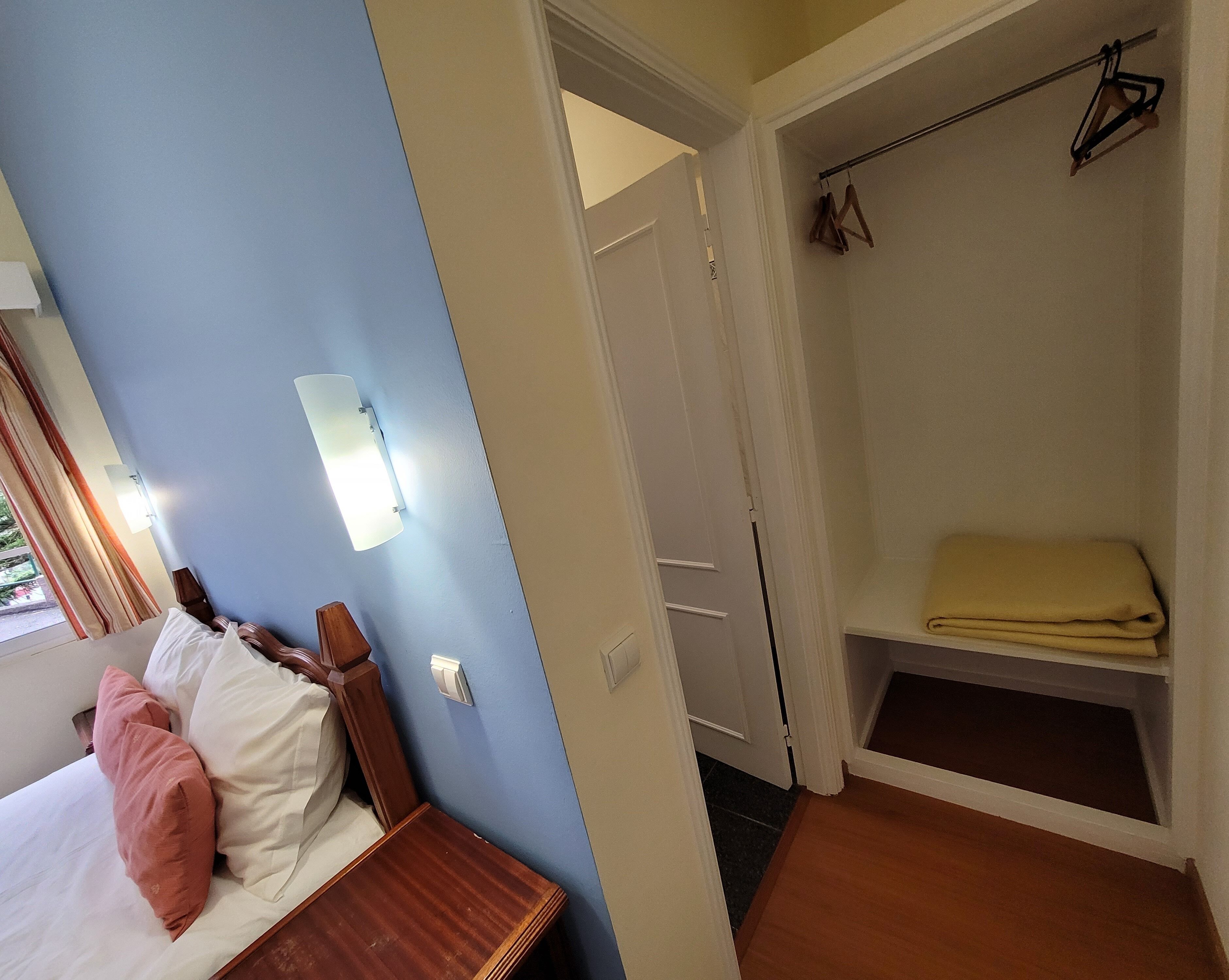 A hotel room with a bed, a nightstand, a wardrobe, and a bathroom visible through an open door.