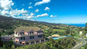 Una casa grande con varios balcones que dan a una piscina y a vistas de la costa.