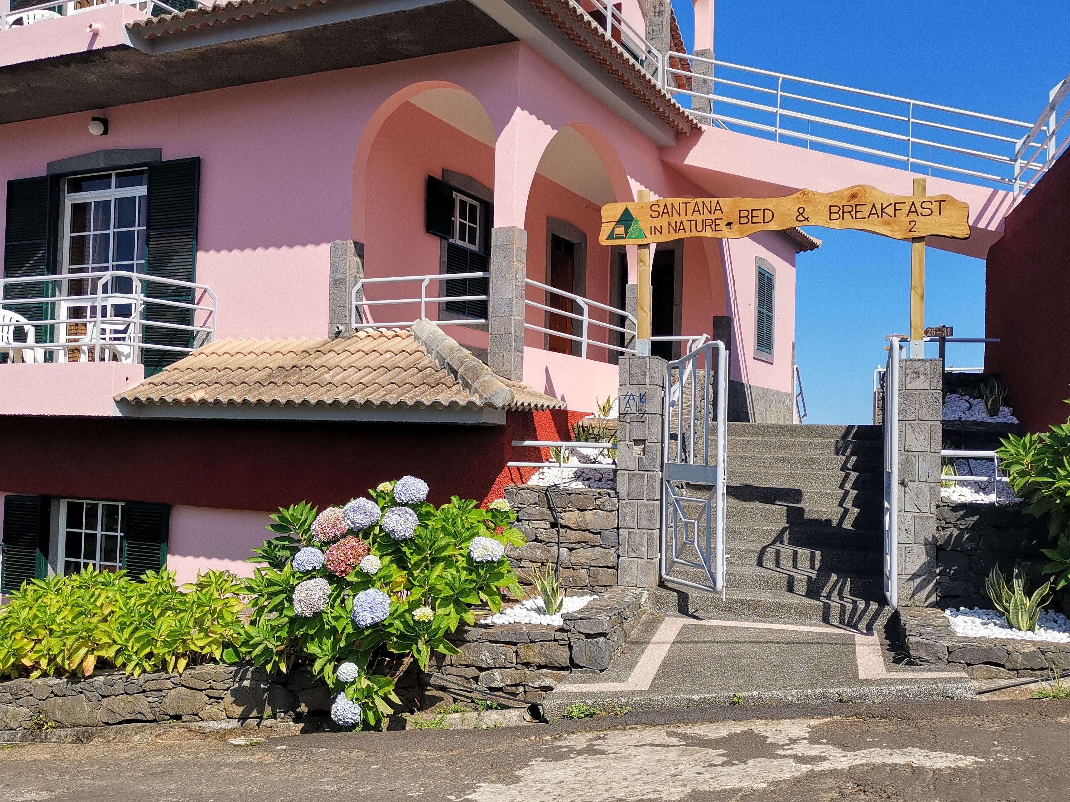A pink building with a sign for 'SANTANA IN NATURE - BED & BREAKFAST'.