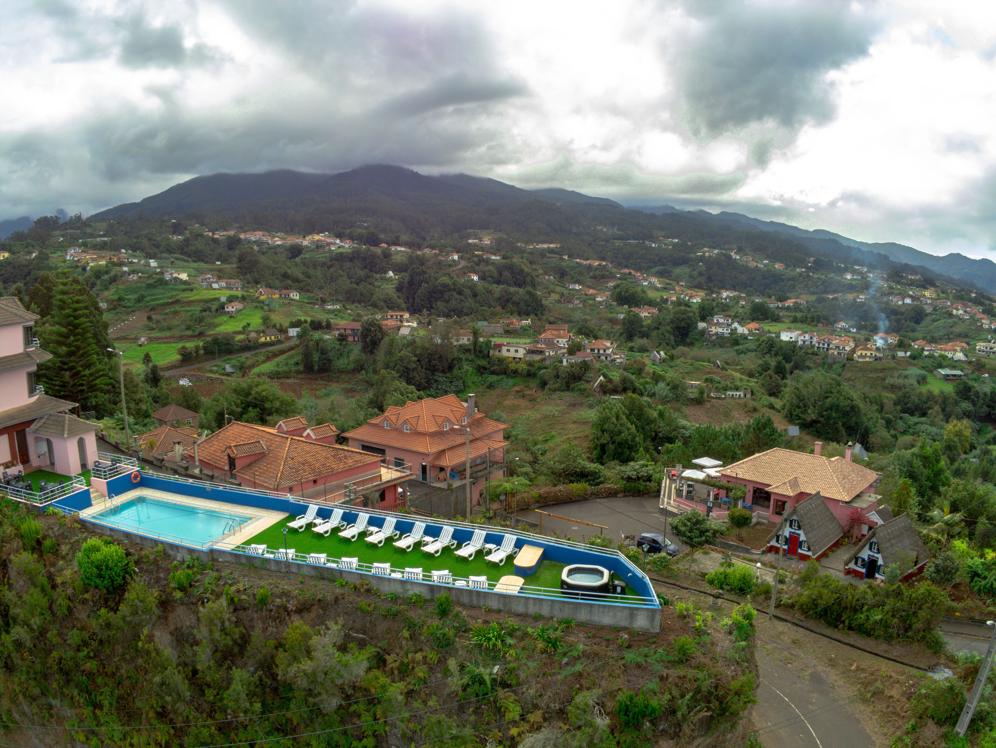A pool area with lounge chairs and a view of a mountainous landscape.
