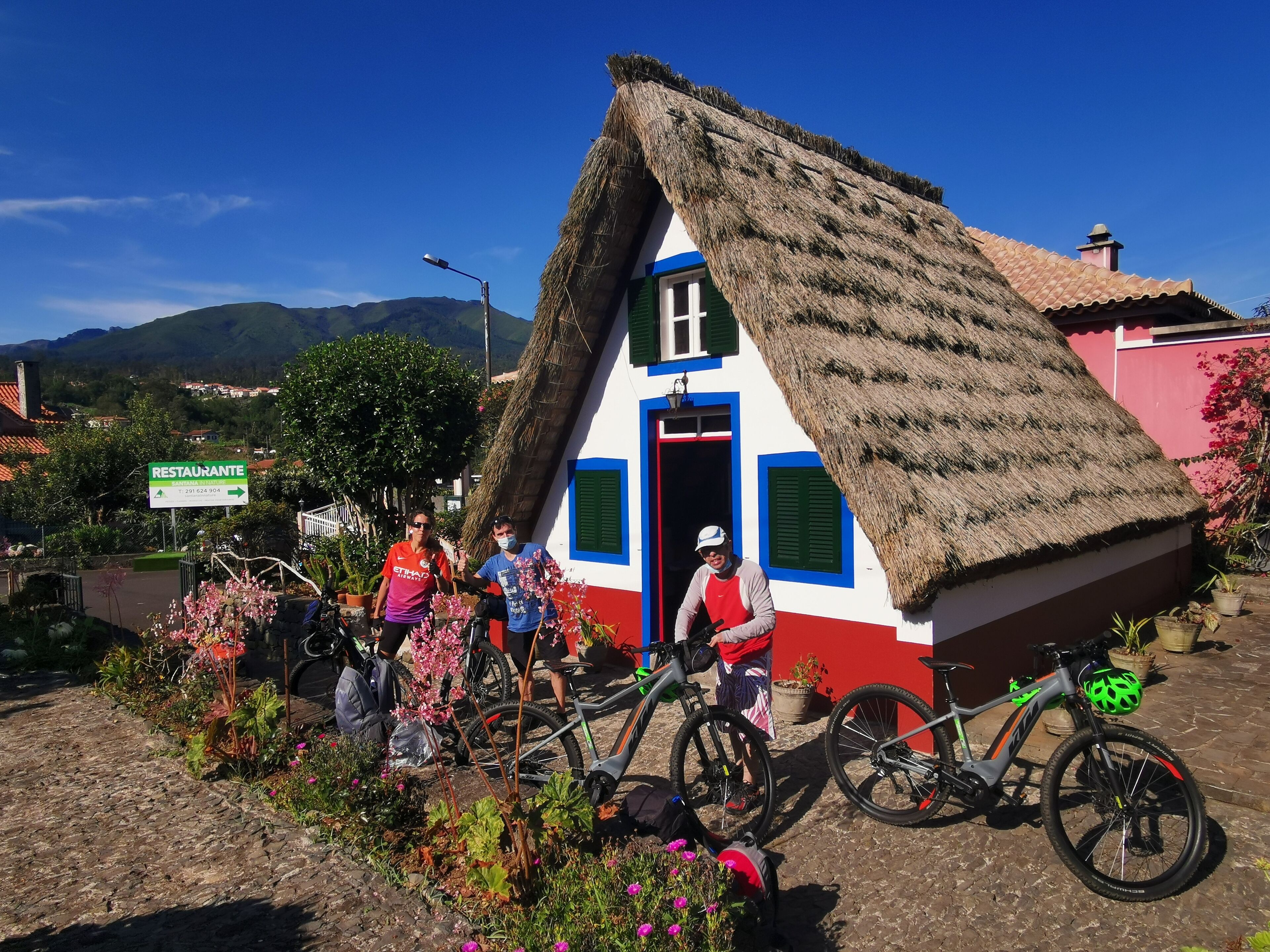A traditional thatched-roof building with a red and white facade, a visible door, and a bicycle parked in front.