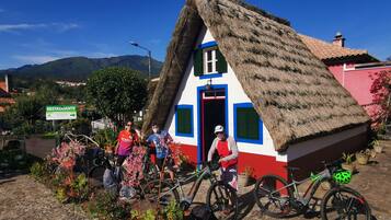 Un edificio tradicional con techo de paja y fachada roja y blanca, con una puerta visible y una bicicleta estacionada adelante.