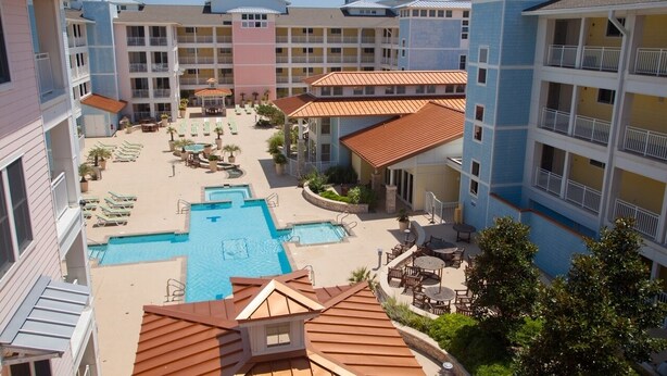 A hotel with multiple balconies, a central pool area, and outdoor seating. - Sandbridge Beach Condo with fantastic Ocean View and Bay View Balcony!  (Virginia Beach)