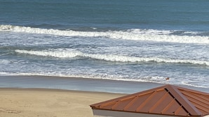 A beach with waves and a building with a brown roof. - Sandbridge Beach Condo with fantastic Ocean View and Bay View Balcony!  (Virginia Beach)