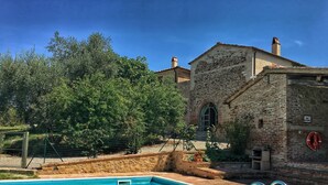 A swimming pool with a stone wall and a brick building in the background.