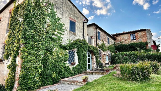 A rustic building with ivy-covered walls, a gravel pathway, and a small outdoor seating area.