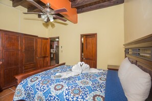 Un dormitorio con cama, armario de madera y ventilador de techo.
