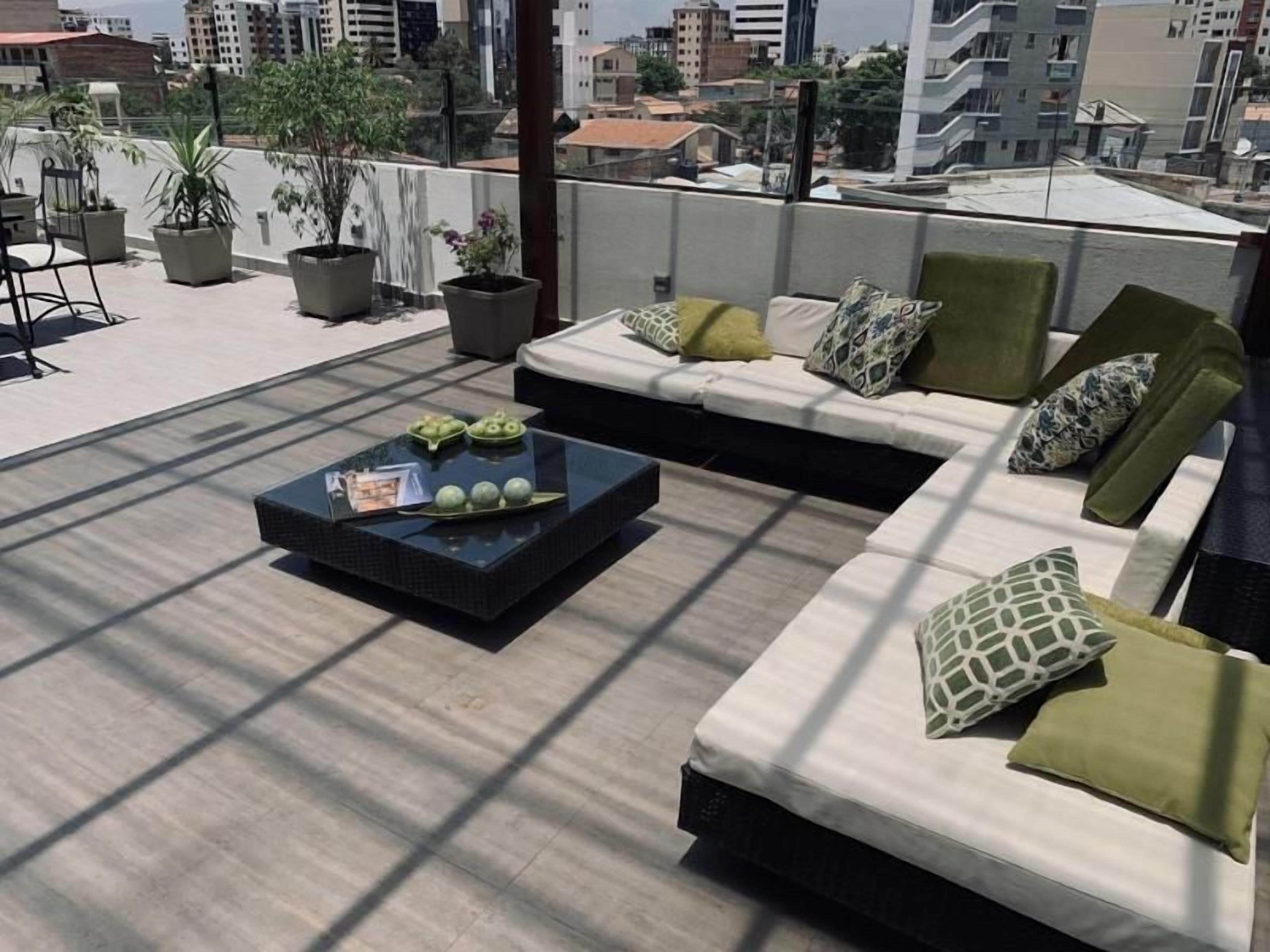 A rooftop terrace with a sofa set, a coffee table, and potted plants.