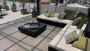 Eine Dachterrasse mit einer Sofagarnitur, einem Couchtisch und Blumentöpfen.
