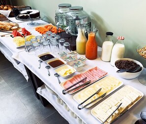 A buffet table with various food items, condiments, and beverages.