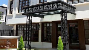 A hotel with a white facade, a sign reading 'DOMANI HOTEL,' and a decorative entrance canopy. - Hotel Boutique Domani (Cochabamba)