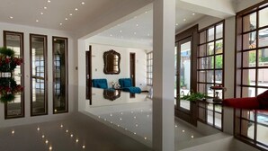A spacious lobby with a reflective floor, large windows, and a seating area with blue sofas. - Hotel Boutique Domani (Cochabamba)