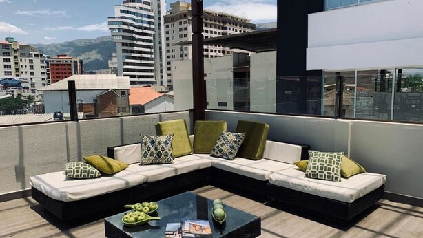A rooftop terrace with a sectional sofa, a coffee table, and a city view. - Hotel Boutique Domani (Cochabamba)