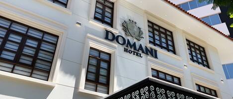 A building with a sign that reads 'DOMANI HOTEL.'