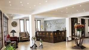 A hotel lobby with a reception desk, seating area, and decorative elements. - Hotel Boutique Domani (Cochabamba)