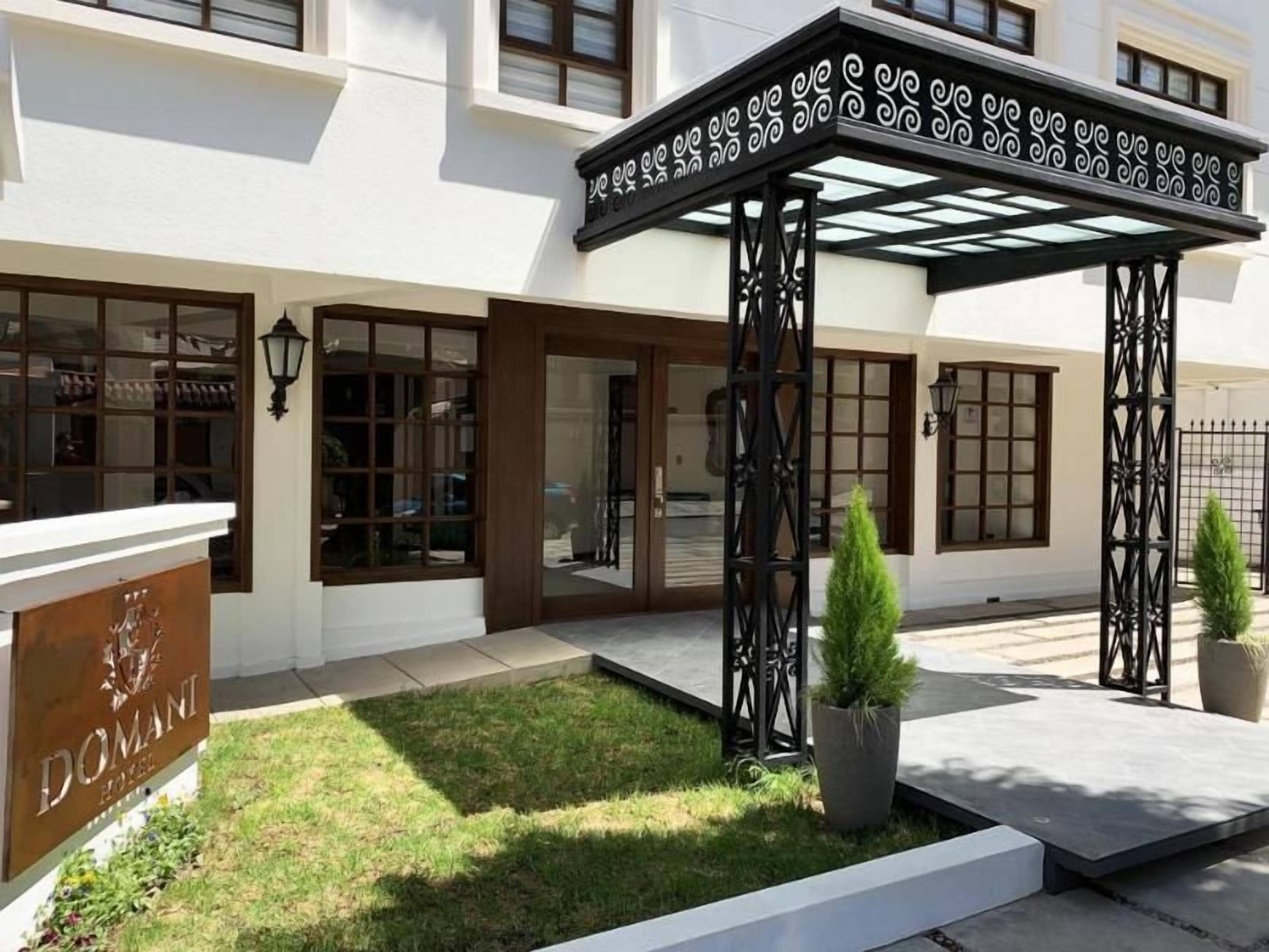 Ein Hotel mit Eingangsbereich, überdachter Terrasse, Schilder und gepflegtem Rasen.