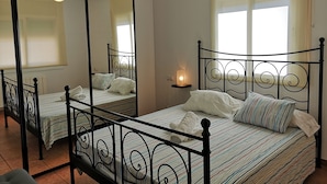 Un dormitorio con dos camas, un ventilador de techo y una lámpara de noche.