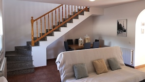 Una sala de estar con escaleras, un comedor y una cama con almohadas.