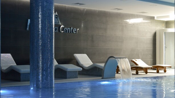 Un área de piscina con sillas de descanso y una fuente de agua.