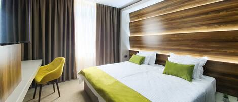 A modern hotel room with a large bed, a desk, and a television.