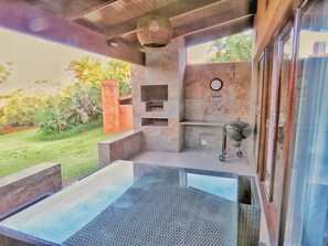 Enjoy al fresco dining in this outdoor patio area with a grill and garden surroundings.