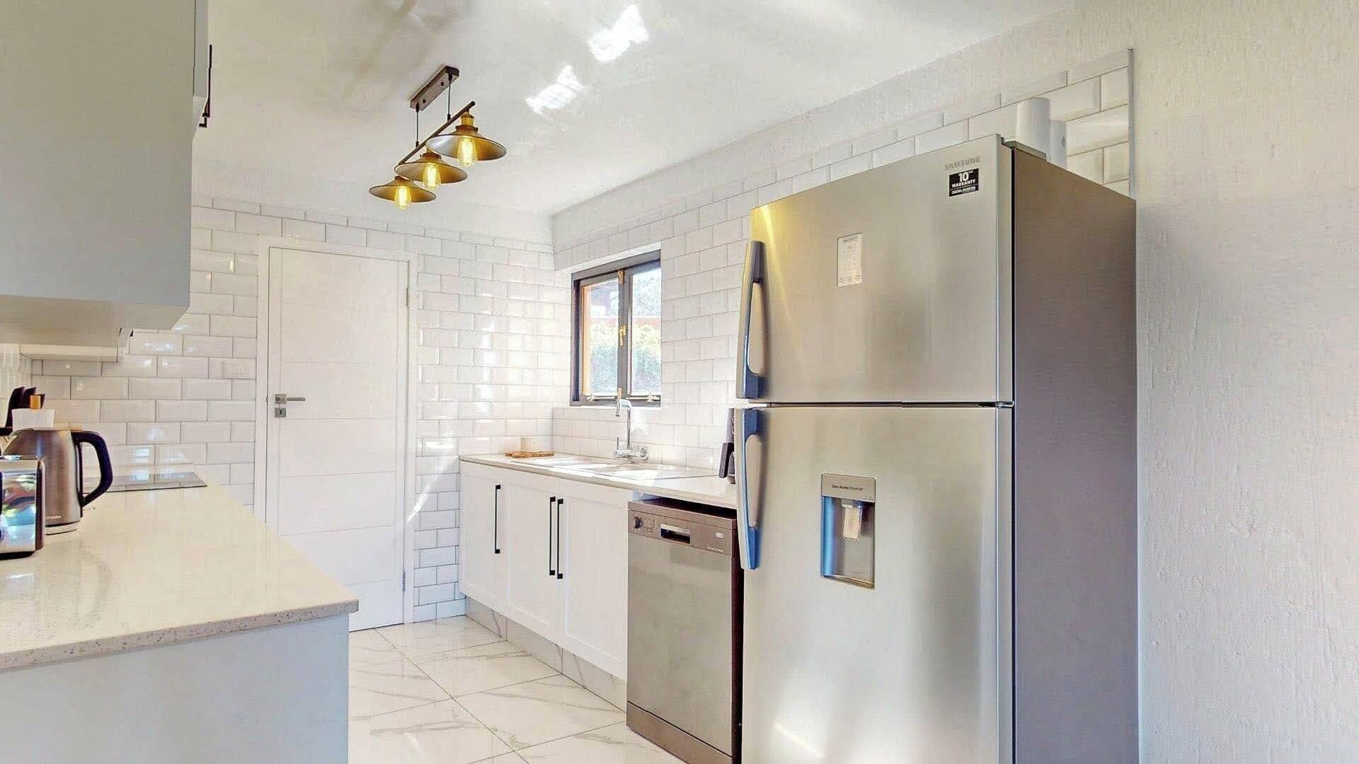 A modern kitchen with white subway tiles, stainless steel appliances, and a pendant light fixture.